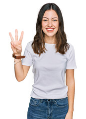 Young beautiful woman wearing casual white t shirt showing and pointing up with fingers number three while smiling confident and happy.