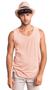 Young hispanic man wearing summer hat relaxed with serious expression on face. simple and natural looking at the camera.