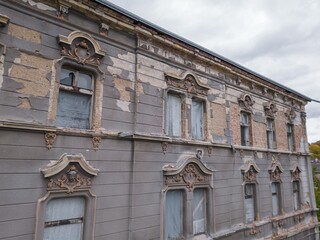 Historic old Early 20th century cupid decorated brick ruined derelict abandoned apartment house building facade