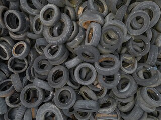 Dump recycling Pile heap stack old used vintage car tyres tires wheels waste dump with some leaves and mud dirt