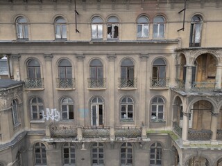 Historic old 19th 20th century ruined derelict abandoned hotel house building  facade scene, with arcade decorated terrace and greek style columns