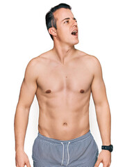 Fototapeta premium Handsome young man wearing swimwear shirtless angry and mad screaming frustrated and furious, shouting with anger. rage and aggressive concept.