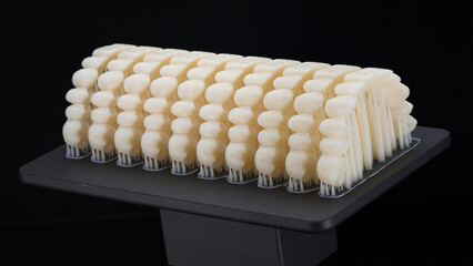 composition of printed dental dentures of the upper jaw on a 3D printer platform on a black...