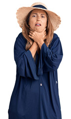 Fototapeta premium Middle age hispanic woman wearing summer hat shouting and suffocate because painful strangle. health problem. asphyxiate and suicide concept.