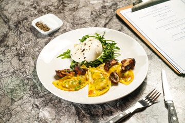 Porcini wontons with buffalo mozzarella and rocket, dip, fork and knife served in plate isolated on marble background side view of hong kong food