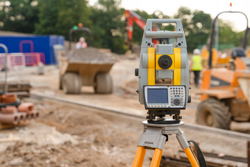 Fototapeta premium Surveying Equipment Set up on Construction Site During Afternoon With Machinery in Background