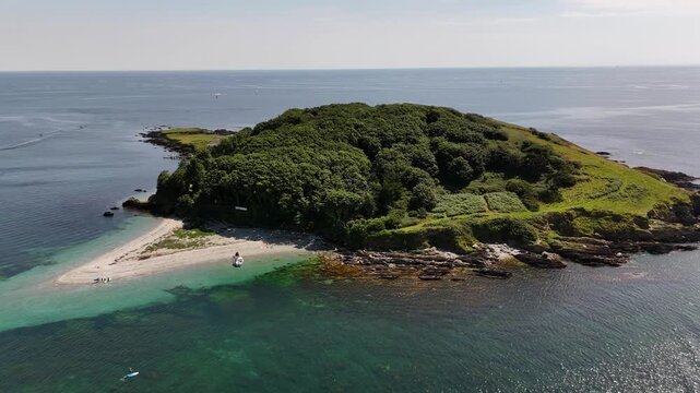 Drone view of the Looe Island surrounded by blue water on a sunny day in Cornwall, England