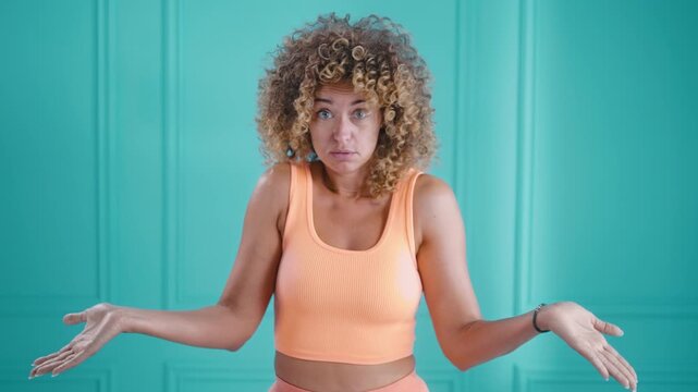 Curly young woman gesturing I don't know or can't help