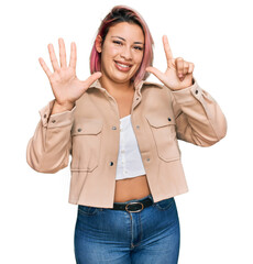 Hispanic woman with pink hair wearing casual clothes showing and pointing up with fingers number seven while smiling confident and happy.