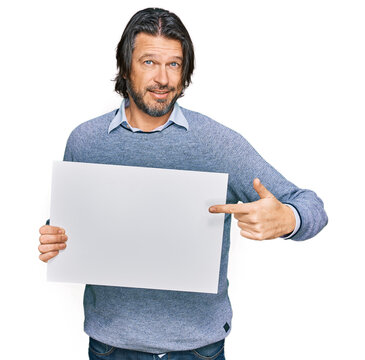 Middle age handsome man holding blank empty banner smiling happy pointing with hand and finger
