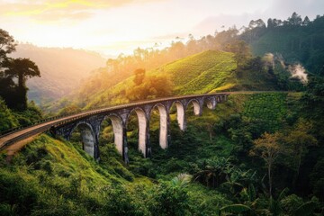 A picturesque railway bridge set against a lush green landscape and rolling hills at dawn.