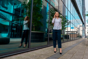 Businesswoman Smiling While Talking on Phone Near Glass Building in City Setting