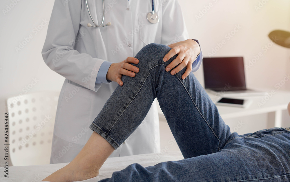 Wall mural doctor and patient are at the medical inspection in clinic. orthopedic examines the knee of a young 