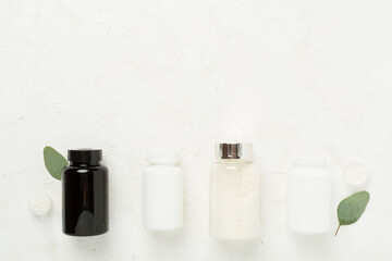 Jars with protein powder on concrete background, top view. Sports nutrition concept