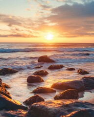 A tranquil sunset over a beach dotted with rocks, showcasing calm waves and a warm sky.