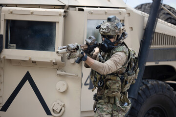 Soldier  in camouflage military uniforms in shooting position  on the side armored fighting car