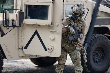 Soldier  in camouflage military uniforms in shooting position  on the side armored fighting car