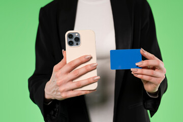 Woman Holding  Mobile Phone and a Blue Card Against Green Background