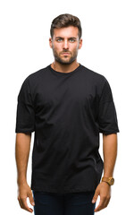 Young handsome man over isolated background with serious expression on face. Simple and natural looking at the camera.