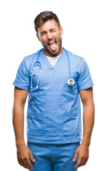 Fototapeta premium Young handsome doctor surgeon man over isolated background sticking tongue out happy with funny expression. Emotion concept.