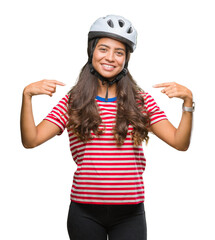 Young arab cyclist woman wearing safety helmet over isolated background looking confident with smile on face, pointing oneself with fingers proud and happy.