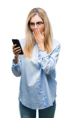Fototapeta premium Young beautiful blonde business woman using smartphone over isolated background cover mouth with hand shocked with shame for mistake, expression of fear, scared in silence, secret concept