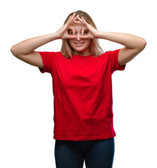 Young caucasian woman over isolated background doing ok gesture like binoculars sticking tongue out, eyes looking through fingers. Crazy expression.