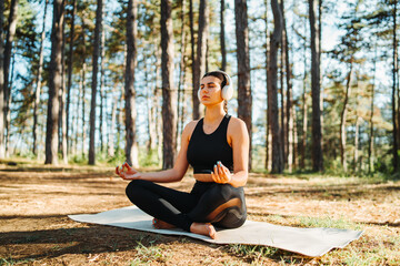 Young caucasian woman doing yoga stretching and meditating in forest

