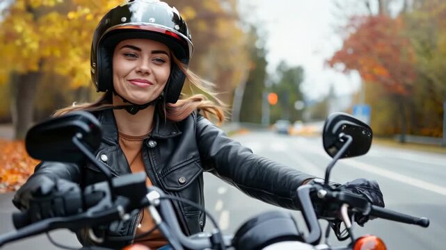 A lively young woman smiles brightly as she rides her motorcycle down a tree-lined street adorned with vibrant fall leaves