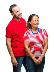 Middle age hispanic couple in love over isolated background looking away to side with smile on face, natural expression. Laughing confident.