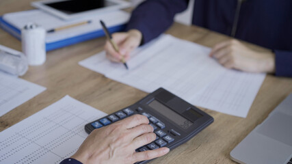 Accountants or auditors reviewing financial documents while sitting at the wooden desk in office.. Audit and taxes concept