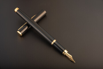 Naklejka premium Fountain pen, beautiful black and gold fountain pen, positioned on dark background, selective focus.
