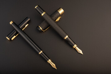 Fountain pens, beautiful black and gold fountain pens, positioned on dark background, selective focus.