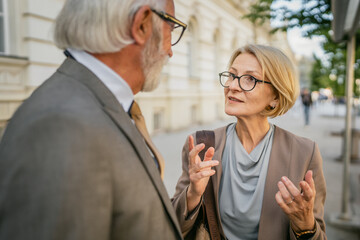 senor man and mature woman meet in city in sunny day talk old friends