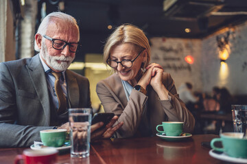 Happy Senior Couple Enjoying Digital Connection use smartphone at Cafe