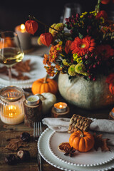 Elegant atmospheric beautiful dinner table setting for thanksgiving or wedding celebration, fall countryside style, pumpkins as decor. Romantic cozy home atmosphere. Wine, floral pumpkin centrepiece.