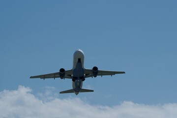 Airplane flying in the blue sky with white clouds on the background