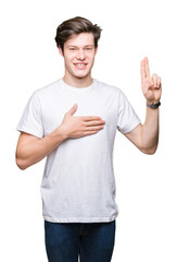 Young handsome man wearing casual white t-shirt over isolated background Swearing with hand on chest and fingers, making a loyalty promise oath