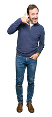 Obraz premium Middle age handsome man wearing a sweater smiling doing phone gesture with hand and fingers like talking on the telephone. Communicating concepts.