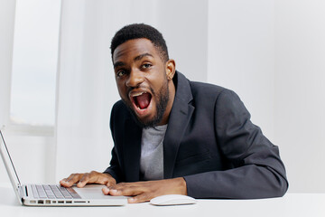 Shocked businessman in suit staring at laptop screen with wide open mouth in office setting