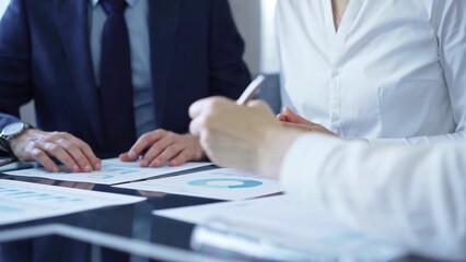 Business people wearing suits are reviewing a financial results and discussing the terms of the agreement. Teamwork and planning