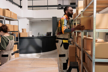 African american worker organizing cardboard boxes, preparing customers orders in warehouse. Diverse storage room employees working in storehouse doing goods inventory inspecting merchandise