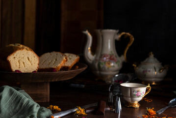 Vanilla pudding or cake on wood with antique tea set and hands sprinkling sugar for snack or breakfast 