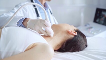 Doctor man is using ultrasound equipment on neck of female patient lying down for a medical examination. Medicine and science