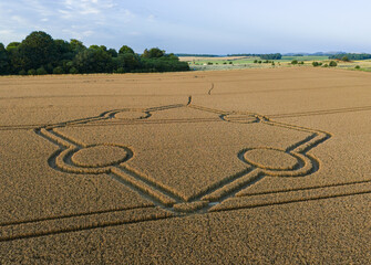Aerial view of an intricate geometric crop circle formation in a wheat field at Normanton Down, near Stonehenge in Wiltshire, England, UK