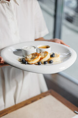 Appetizing cheese pancakes with blueberries and honey on a large white plate