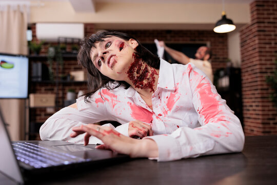 Woman dead on office desk chair in front of notebook after being worked to death, karoshi concept. Lifeless businesswoman looking like undead zombie, victim of corporate rat race grinding