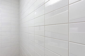 Public restroom with gray and white tile stalls, sink and lavatories