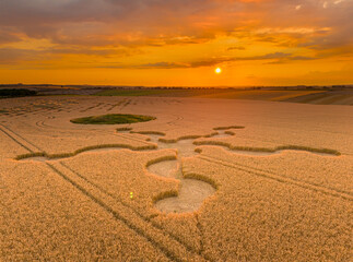 Aerial view of an intricate geometric crop circle formation in a wheat field near Stonehenge in...
