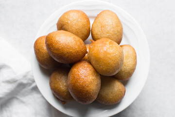 Overhead view of nigerian puff-puff on a white plate, nigerian fried dough balls, flatlay of homemade bofrot on white dish